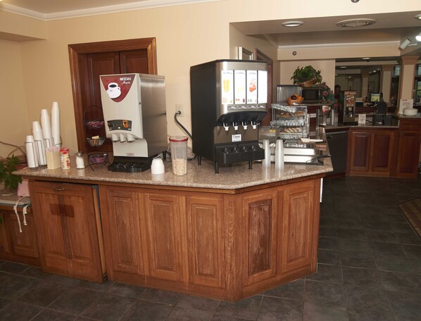 A kitchen area with a coffee station featuring a Nescafé Dolce Gusto machine, a refrigerator, and a microwave. - New World Inn (Barre)