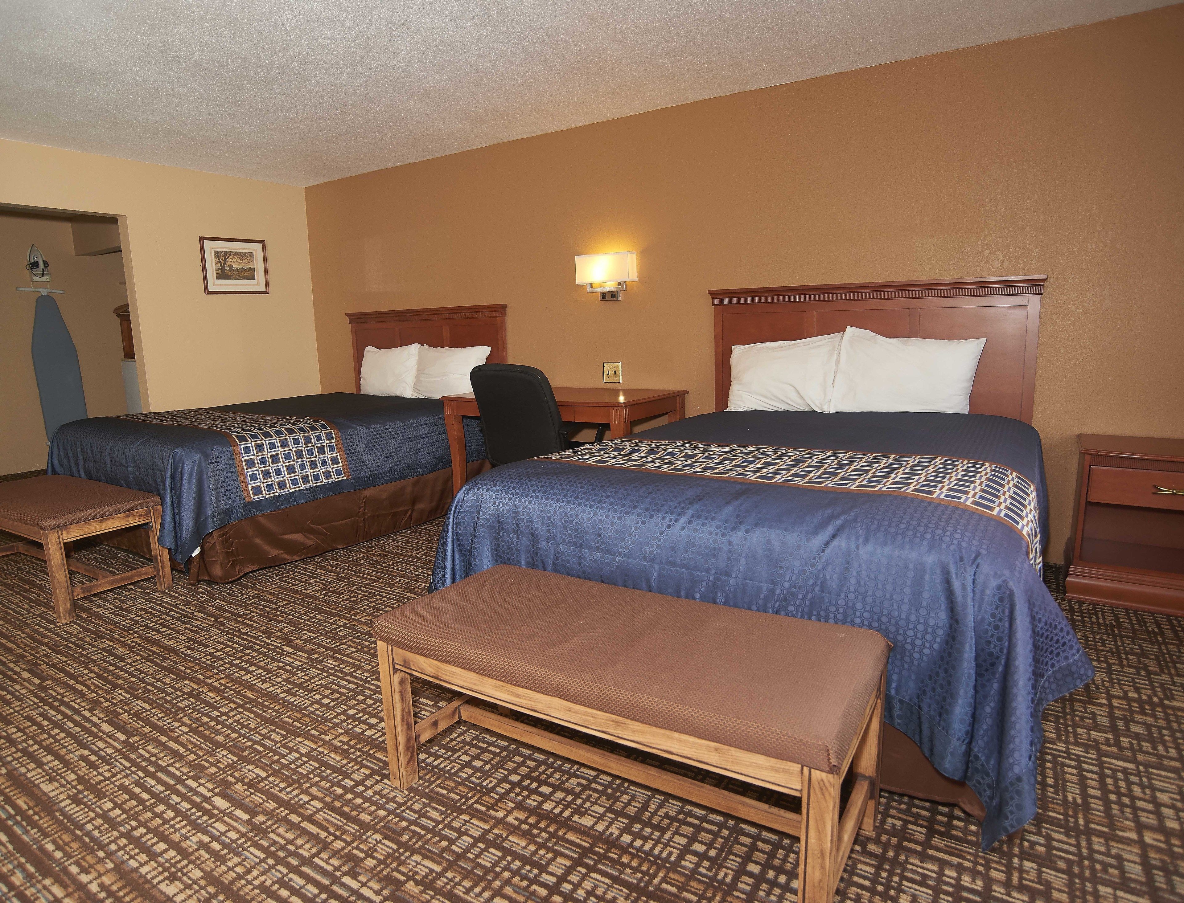 Een hotelkamer met twee bedden, een bureau, een stoel en een bank.