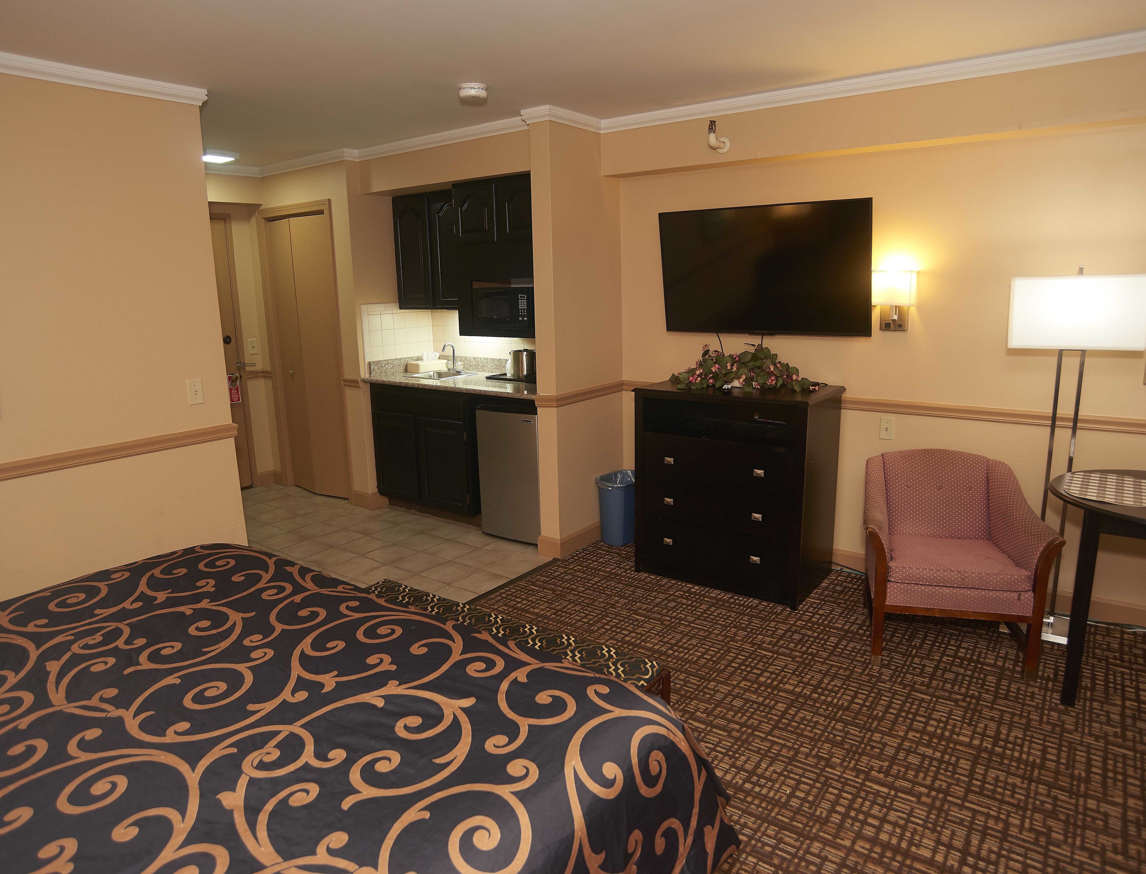 Una habitación de hotel con una cama, un escritorio con una computadora, una silla y un televisor.