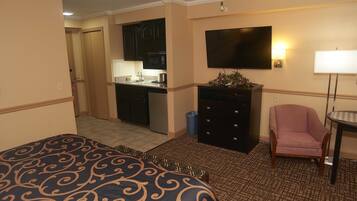 Una habitación de hotel con una cama, un escritorio con una computadora, una silla y un televisor.