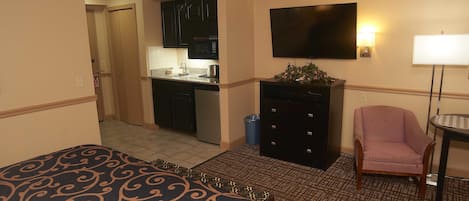A hotel room with a bed, a desk with a computer, a chair, and a TV.
