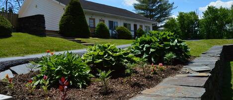 A residential house with a stone pathway and well-maintained garden beds.