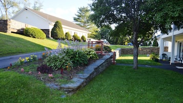 A residential area with a stone retaining wall, a well-maintained lawn, and a house with a porch.