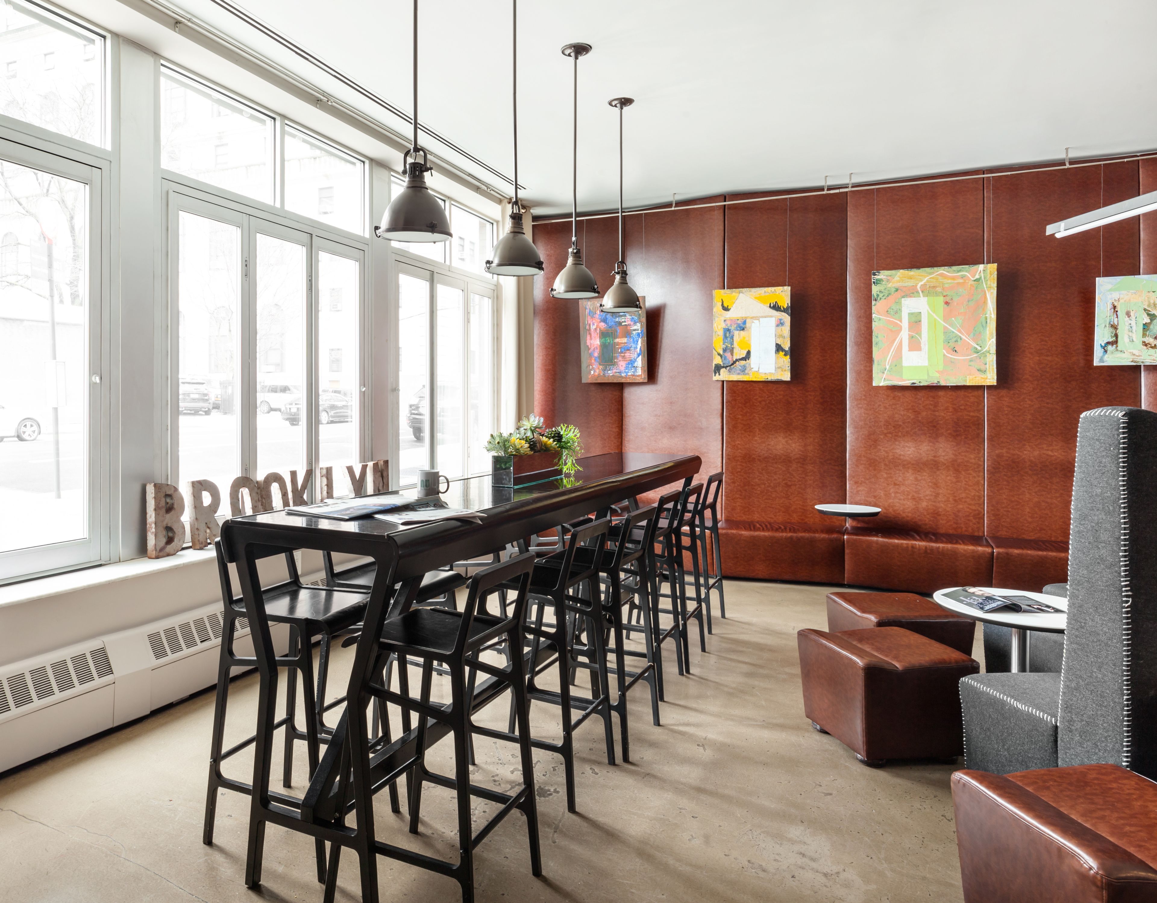 Ein modernes Interieur mit einer langen Bar, mehreren Stühlen, einer Couch und Kunstwerken an den Wänden.