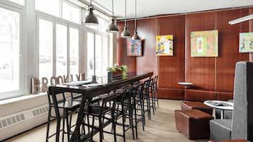 Ein modernes Interieur mit einer langen Bar, mehreren Stühlen, einer Couch und Kunstwerken an den Wänden.