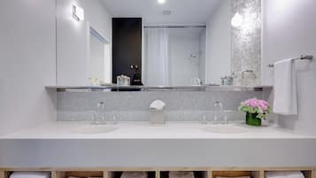Une salle de bain moderne avec deux lavabos, un grand miroir et une douche.