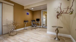 A hotel room with a large window, a desk with a computer, a chair, a small table, and a decorative branch on the wall. - Quality Inn & Suites Capitola By the Sea (Capitola)