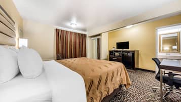 A hotel room with a bed, a desk, a television, and a mirror.
