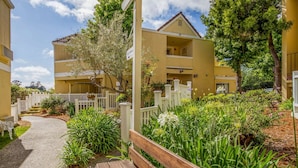 A residential building with a paved pathway, wooden benches, and lush greenery. - Quality Inn & Suites Capitola By the Sea (Capitola)