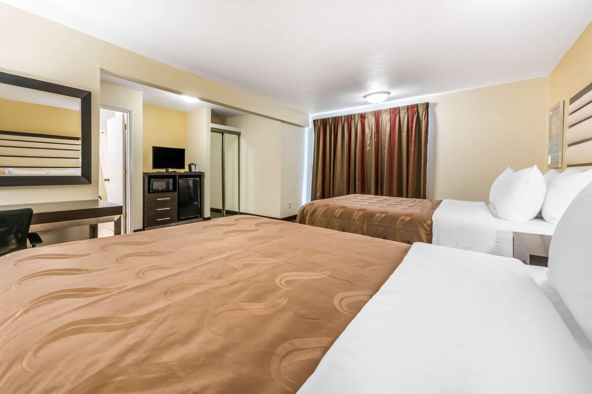 A hotel room with two beds, a desk, a television, and a wardrobe.