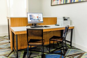 Habitación de hotel con escritorio, computadora, impresora y dos sillas.
