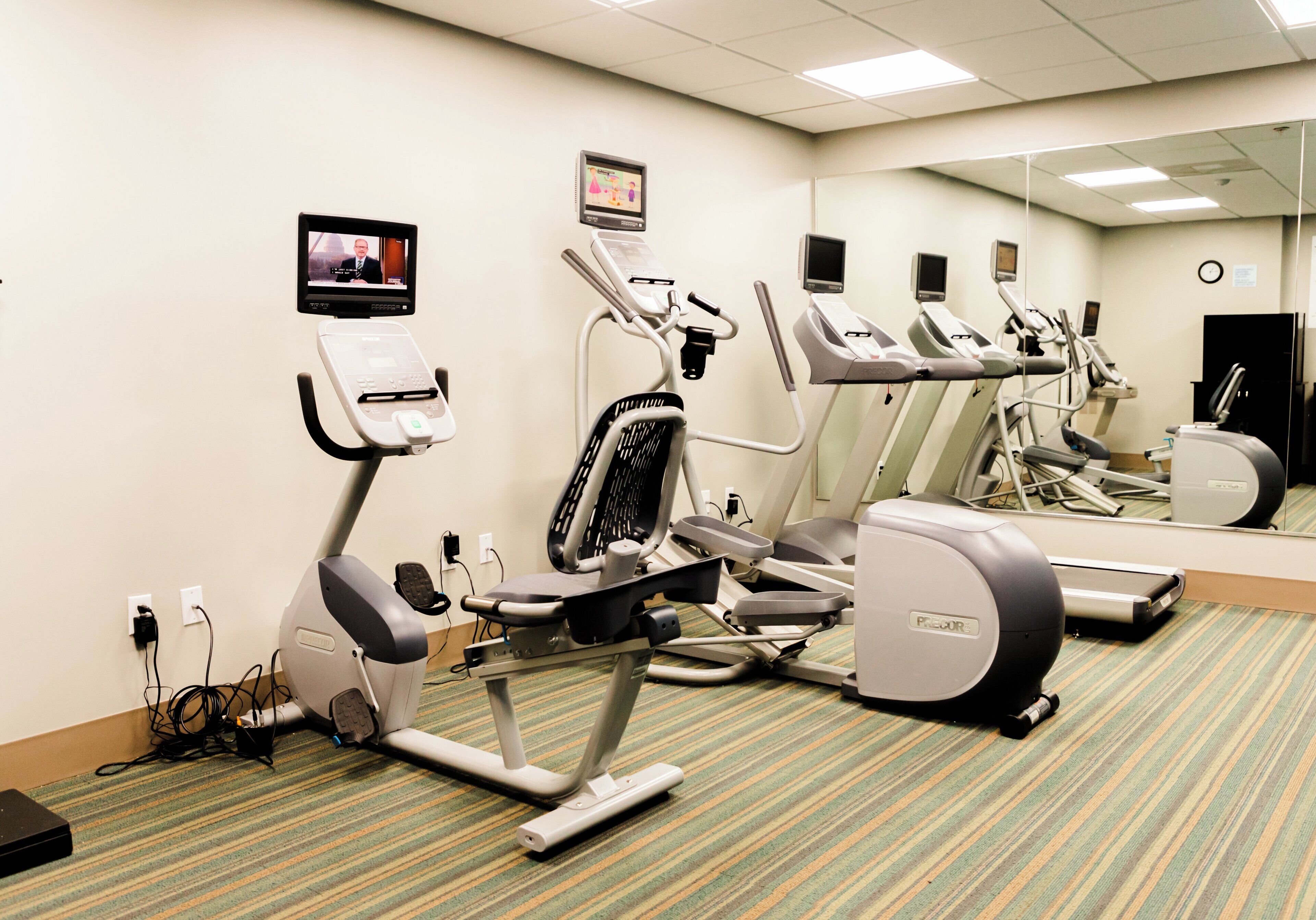 Une salle de remise en forme équipée de tapis de course, d’un vélo d’appartement et d’un rameur.
