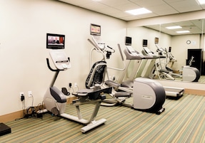 Un gimnasio con cintas de correr, una bicicleta estática y una máquina de remo.