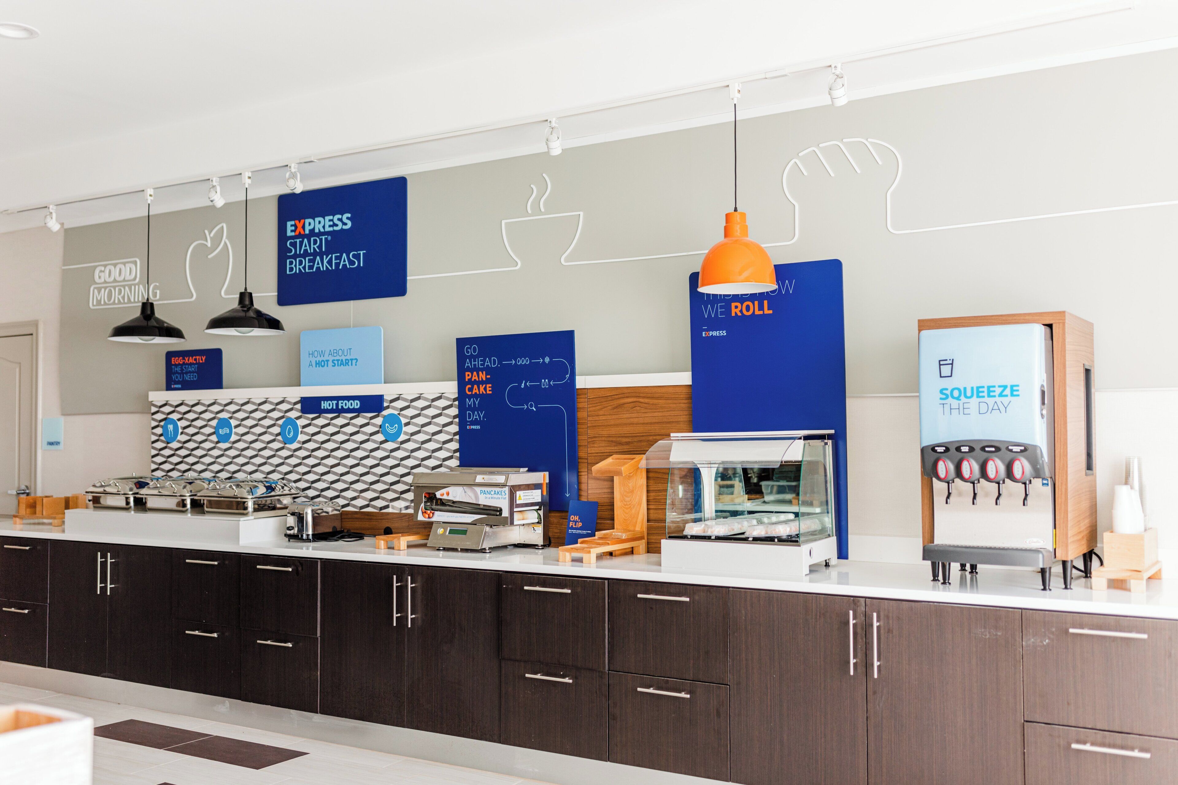 A modern breakfast bar with a variety of food options, including a coffee machine and a juice dispenser.