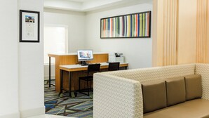 A hotel room with a desk, a computer, a printer, a sofa, and a colorful striped artwork on the wall. - Holiday Inn Express Greenville by IHG (Greenville)