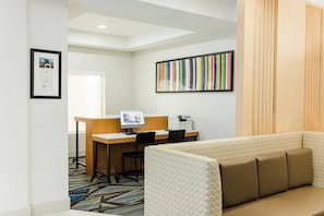 A hotel room with a desk, a computer, a printer, a sofa, and a colorful striped artwork on the wall. - Holiday Inn Express Greenville by IHG (Greenville)