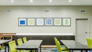 A conference room with a long table, green chairs, and framed wall art. - Holiday Inn Express Greenville by IHG (Greenville)
