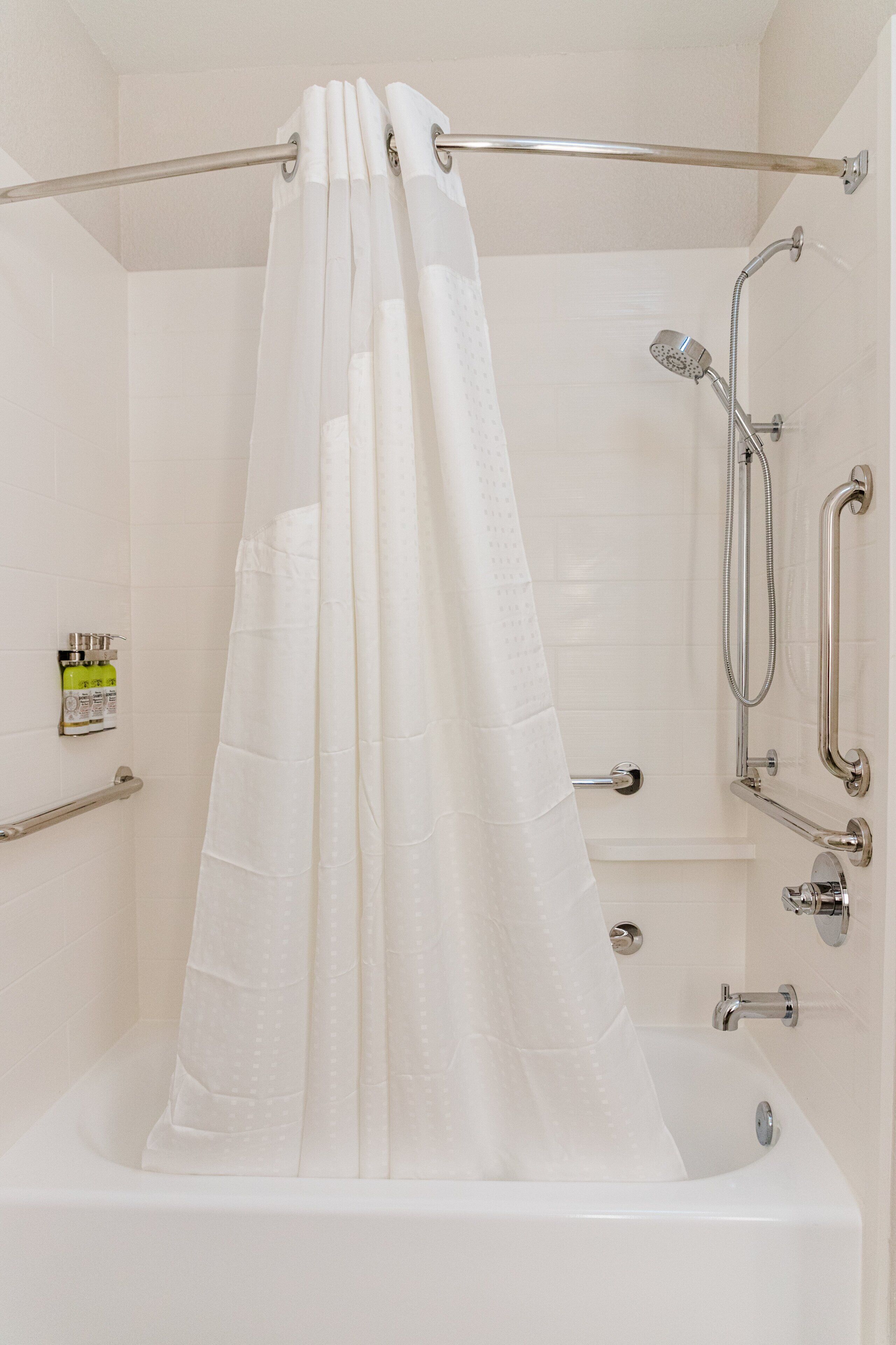 Un baño moderno con bañera, ducha y barras de apoyo.