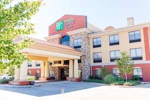 A Holiday Inn Express & Suites building with a brick facade, large windows, and a covered entrance area.