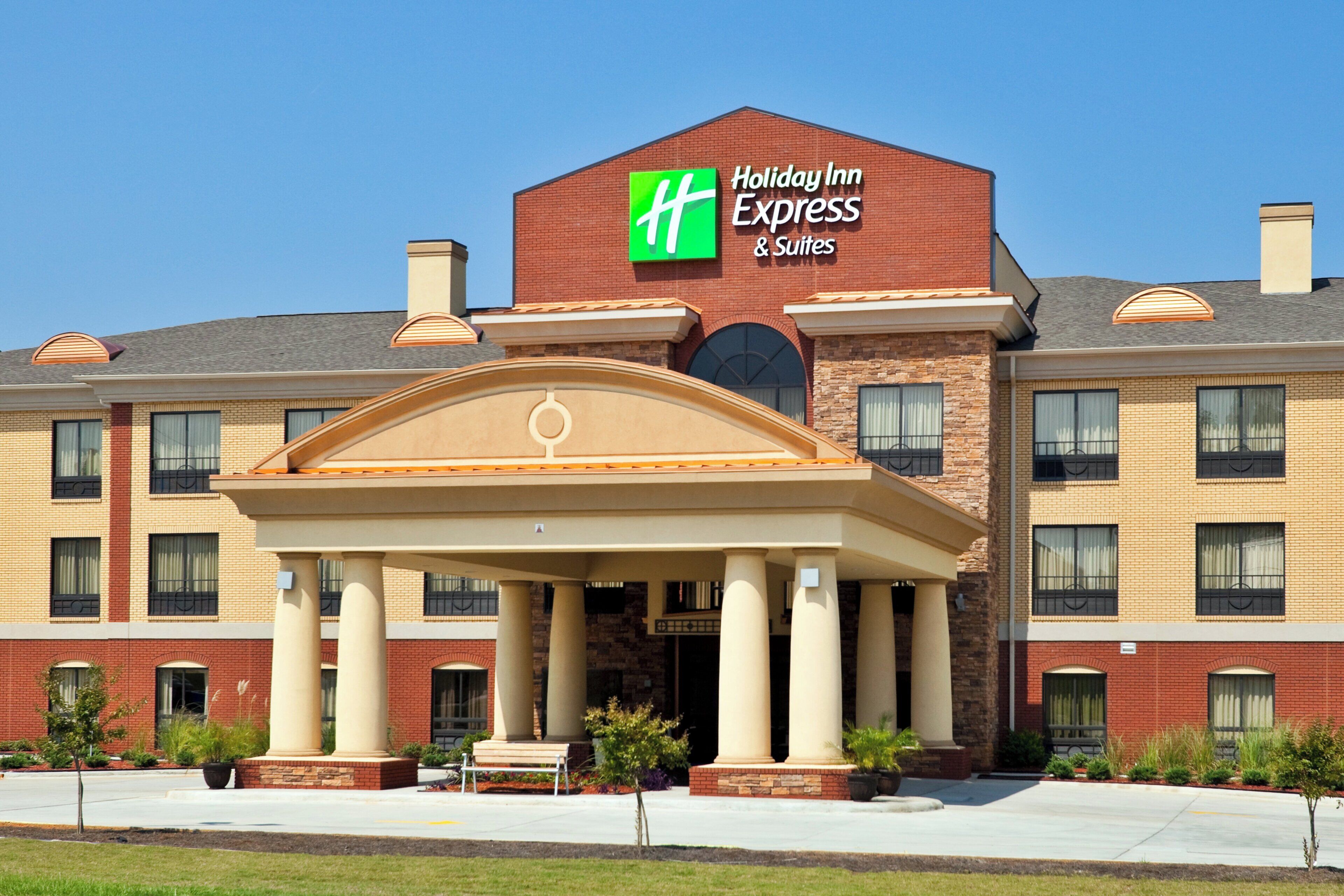 A Holiday Inn Express & Suites hotel with a prominent entrance, multiple windows, and a brick facade.