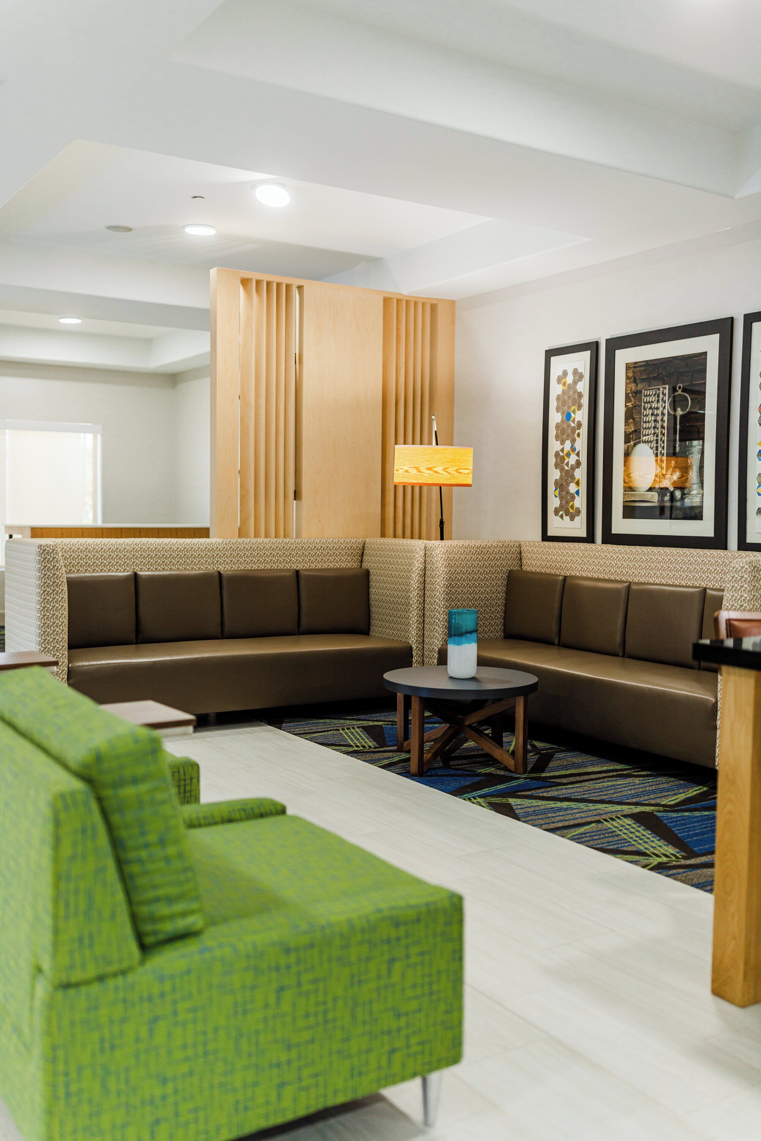 A modern living room with a sectional sofa, a green armchair, a coffee table, and a lamp.