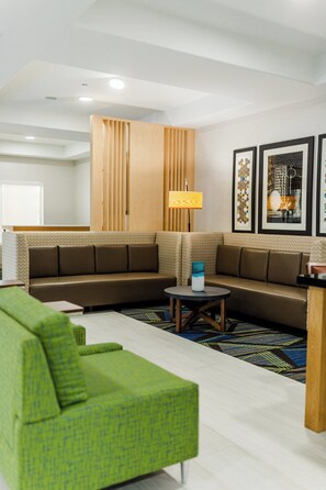 Uma sala de estar moderna com um sofá seccional, uma poltrona verde, uma mesa de centro e uma luminária.