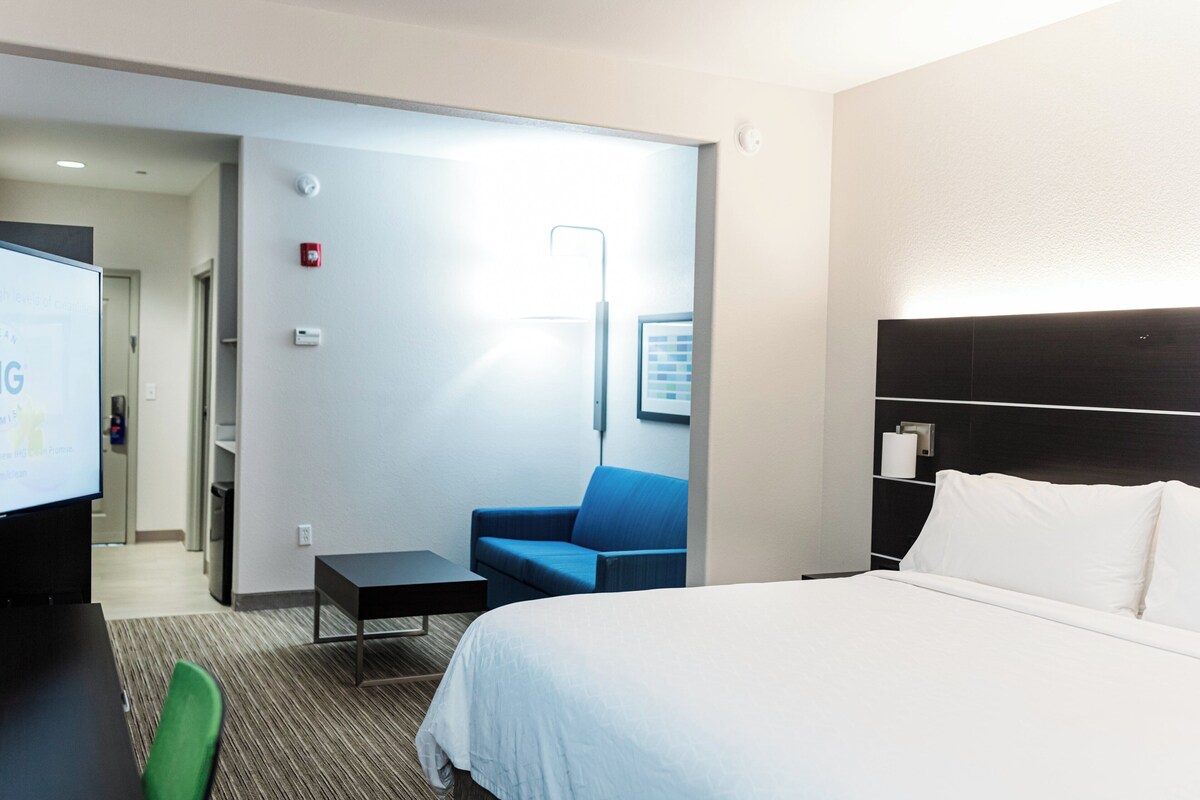 A hotel room with a bed, a desk, a chair, and a television.