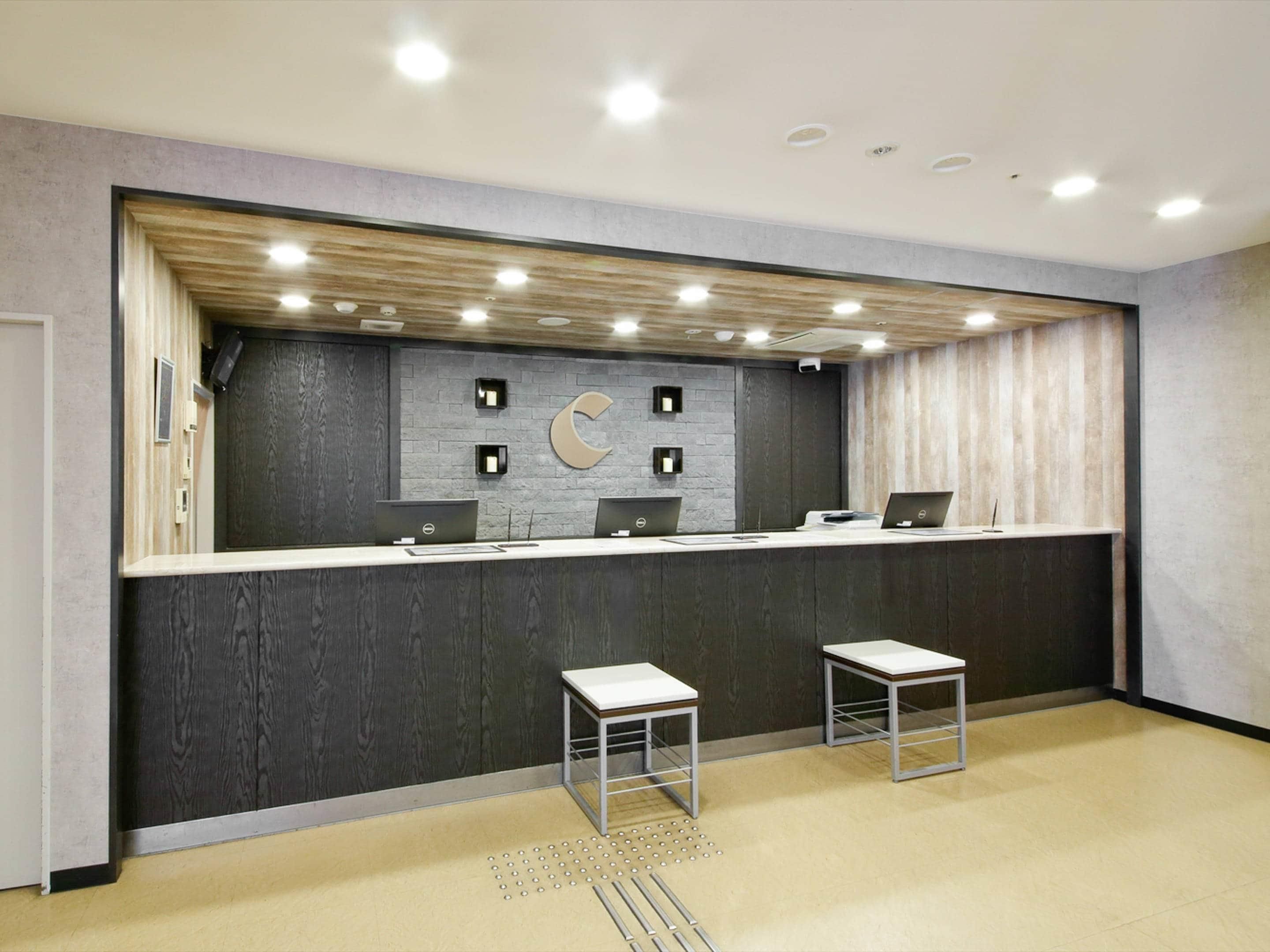 Zona de recepción con mostrador, dos escritorios y una decoración en forma de luna creciente en la pared.