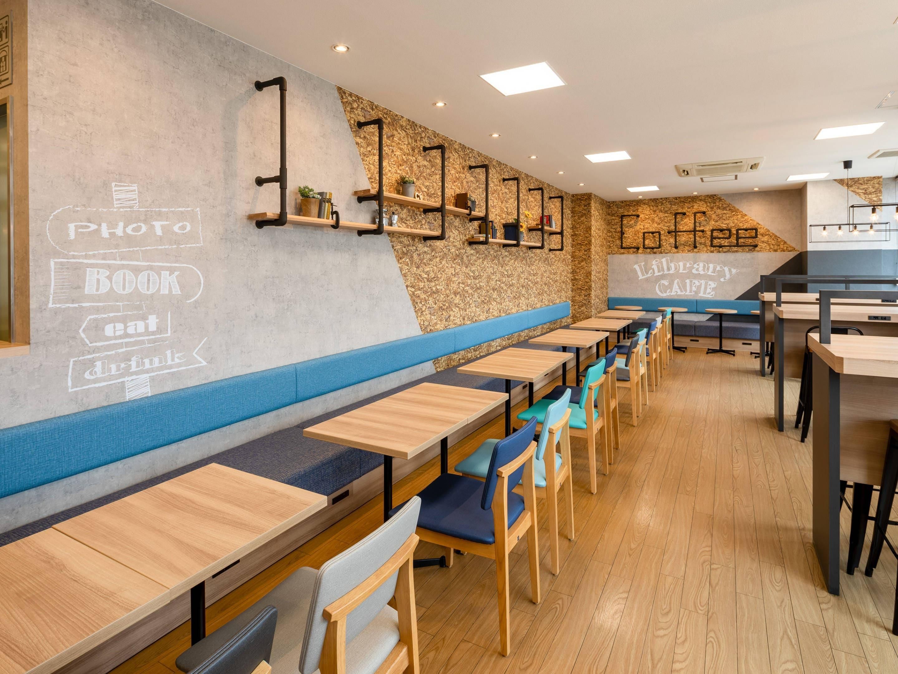 Een modern café met houten tafels en blauwe zittingen met kussens.