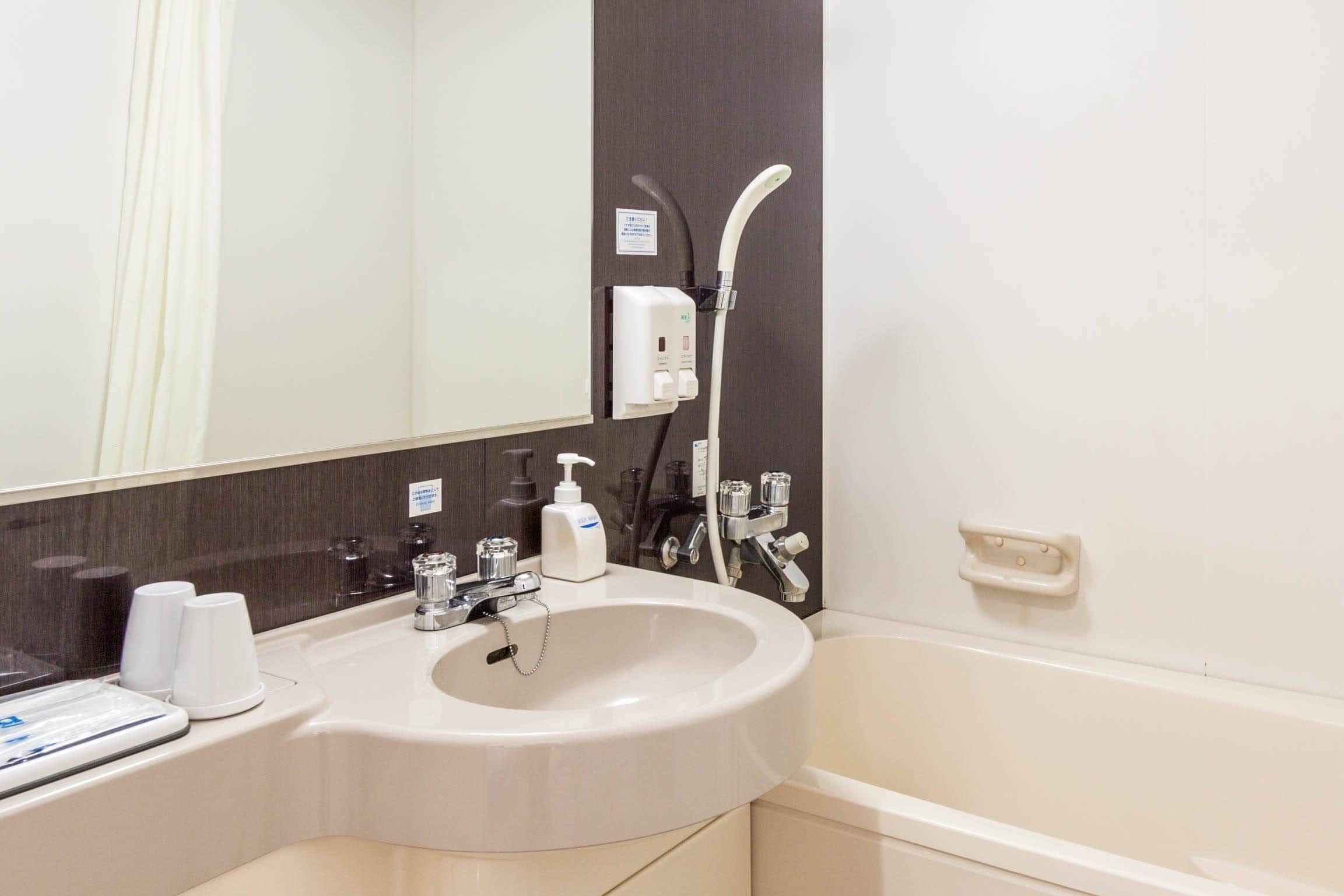 A bathroom with a sink, mirror, and shower.