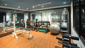 Un gimnasio con equipo de ejercicio, espejos y suelo de madera.