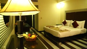 Habitación de hotel con cama, lámpara de noche, frutero y mesita de noche.