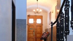 A hallway with a wooden double door marked 'EXIT', a tiled floor, and a staircase with ornate black railings. - Pension Prague City (Prague)