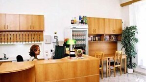 A kitchen with wooden cabinets, a refrigerator, a dining table with chairs, and a potted plant. - Pension Prague City (Prague)