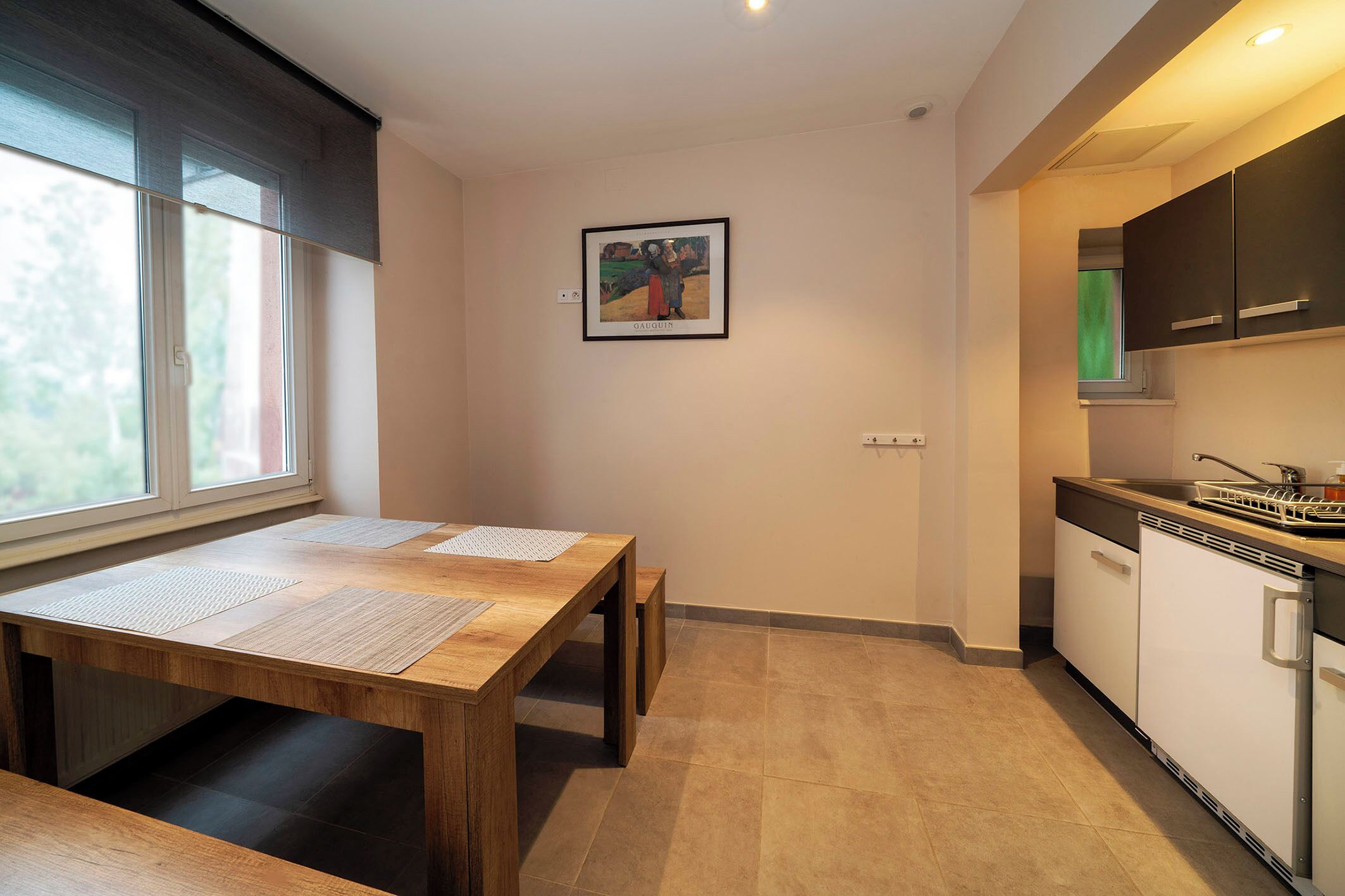 Una cocina moderna con una mesa de madera, armarios, una ventana y una obra de arte enmarcada en la pared.