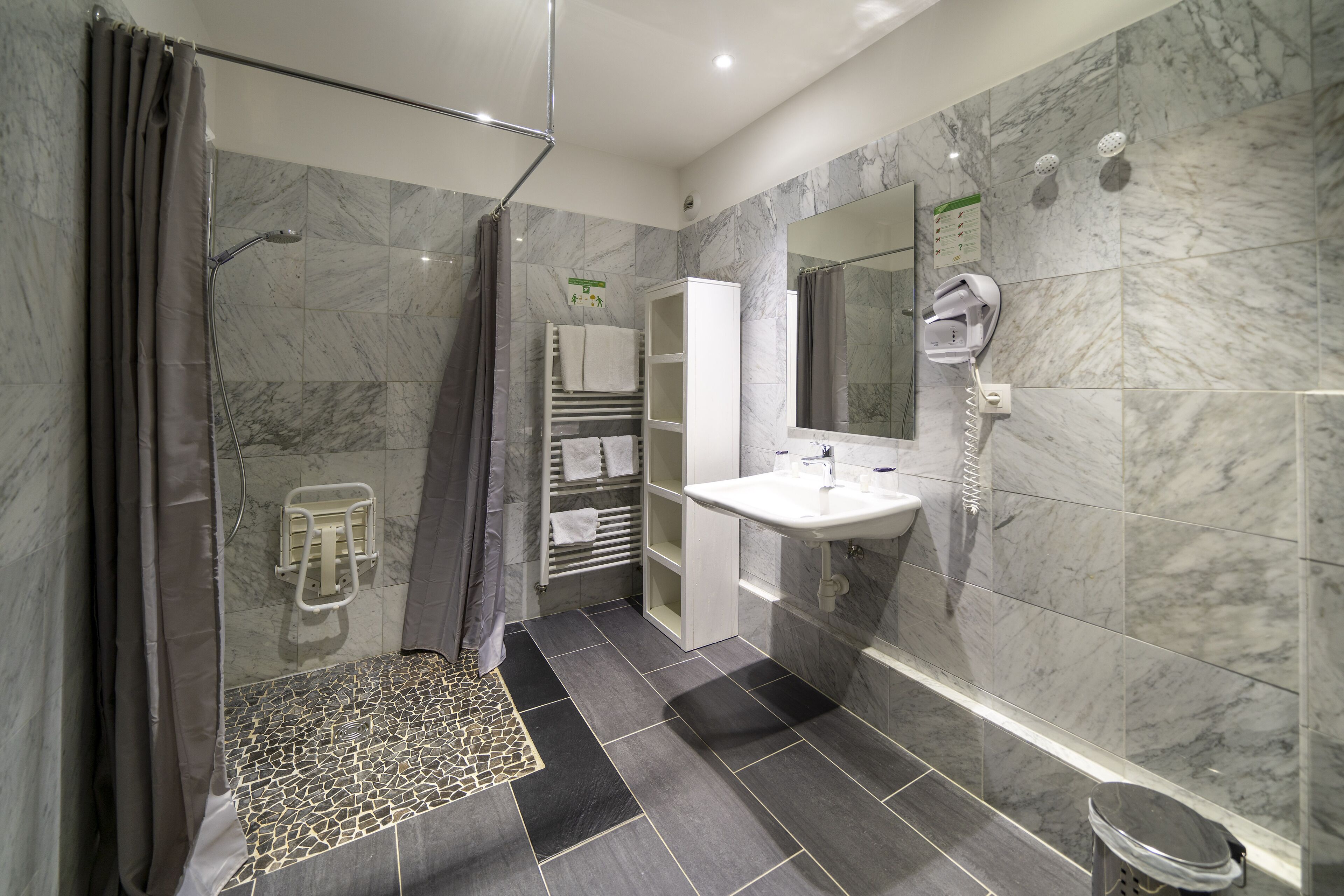 Een moderne badkamer met een douche, een wastafel en een spiegel.
