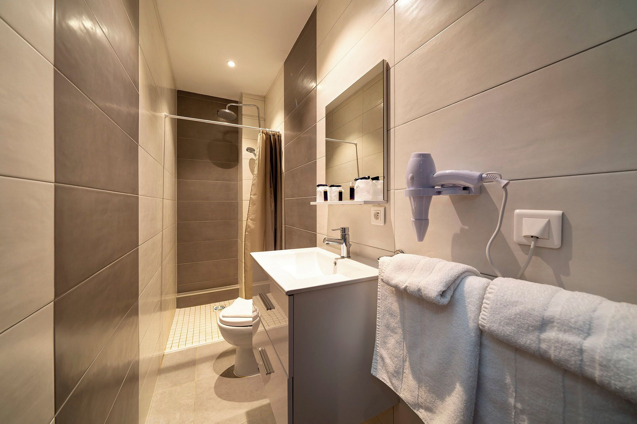 A modern bathroom with a shower, toilet, sink, and towel rack.