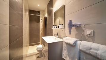 Un baño moderno con ducha, inodoro, lavabo y toallero.