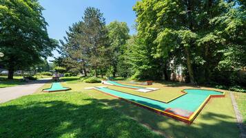 A miniature golf course with multiple holes, surrounded by lush greenery and trees.