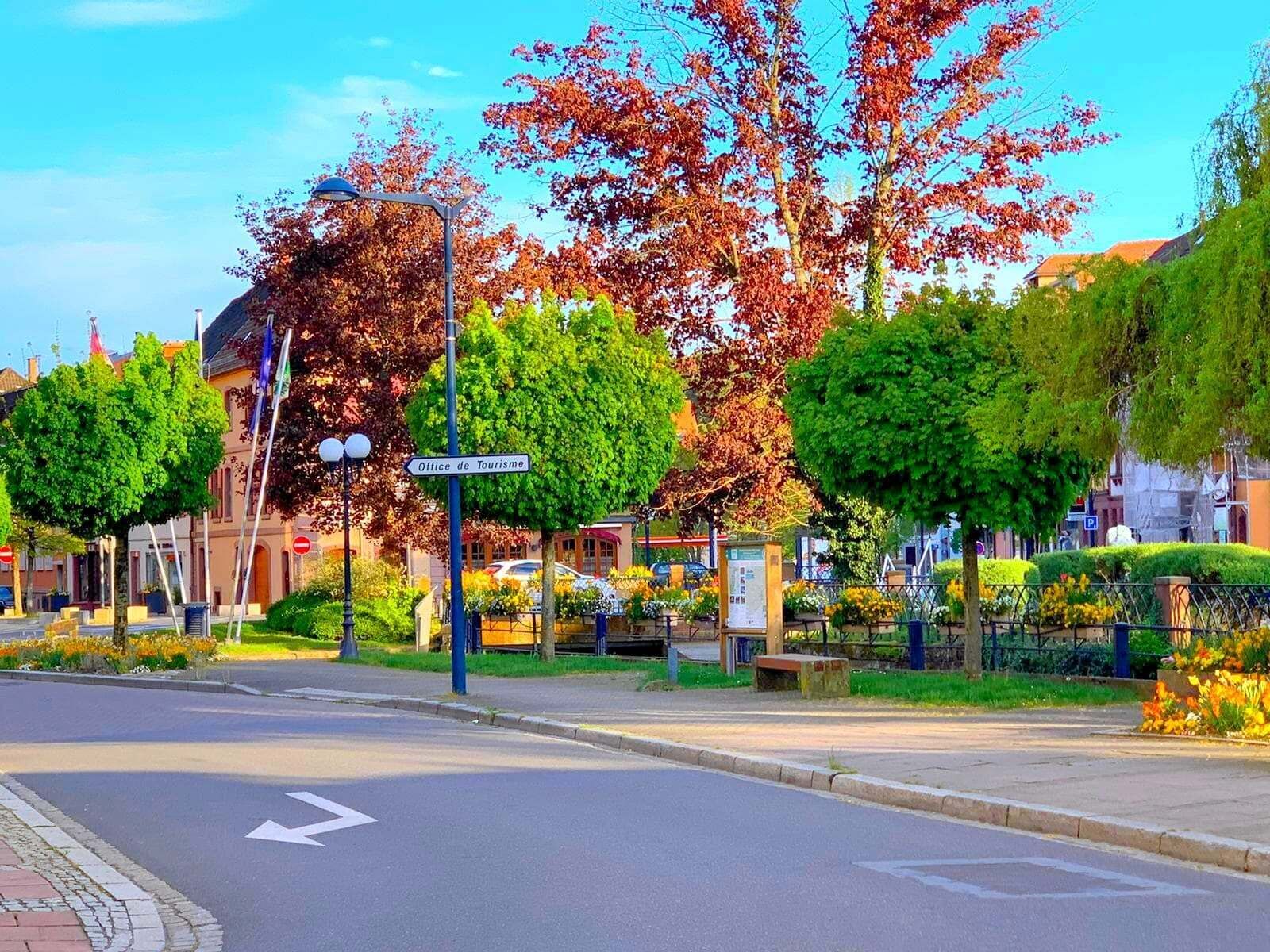 Une rue avec une enseigne indiquant « Office de tourisme » et une flèche directionnelle sur la chaussée.