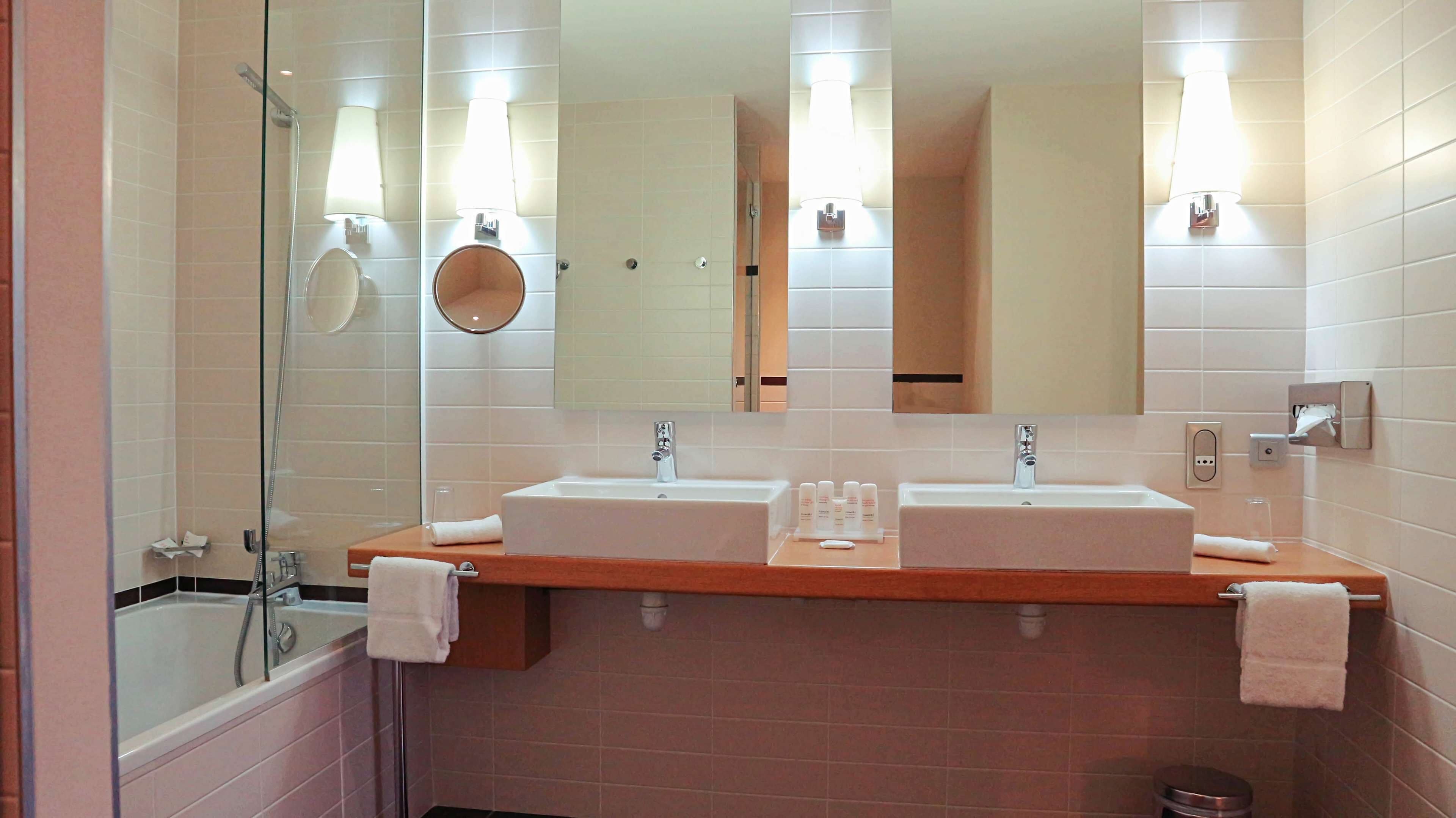Baño con dos lavamanos, cabina de ducha de vidrio y espejo con iluminación.