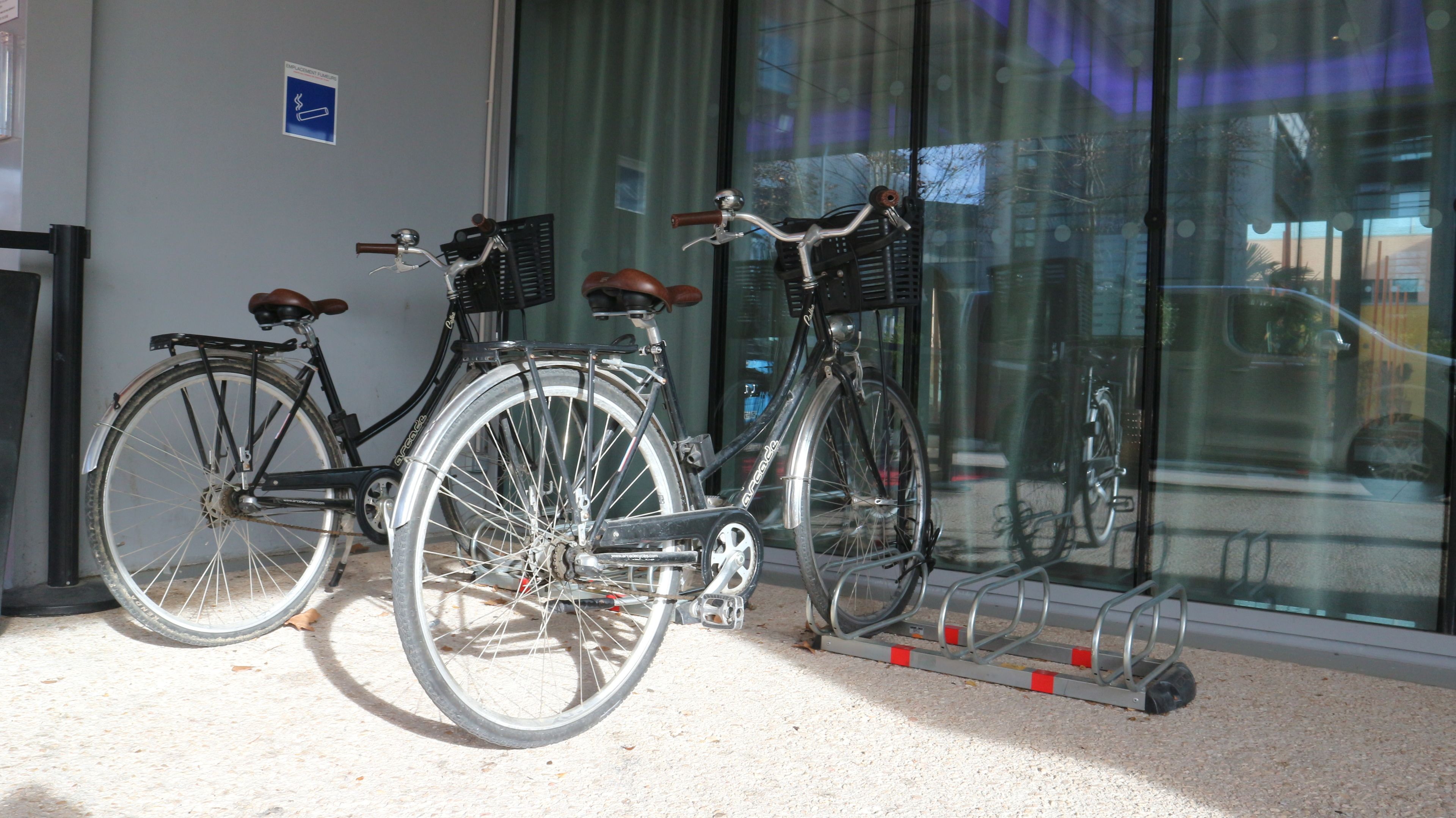Two bicycles parked indoors with a window in the background.