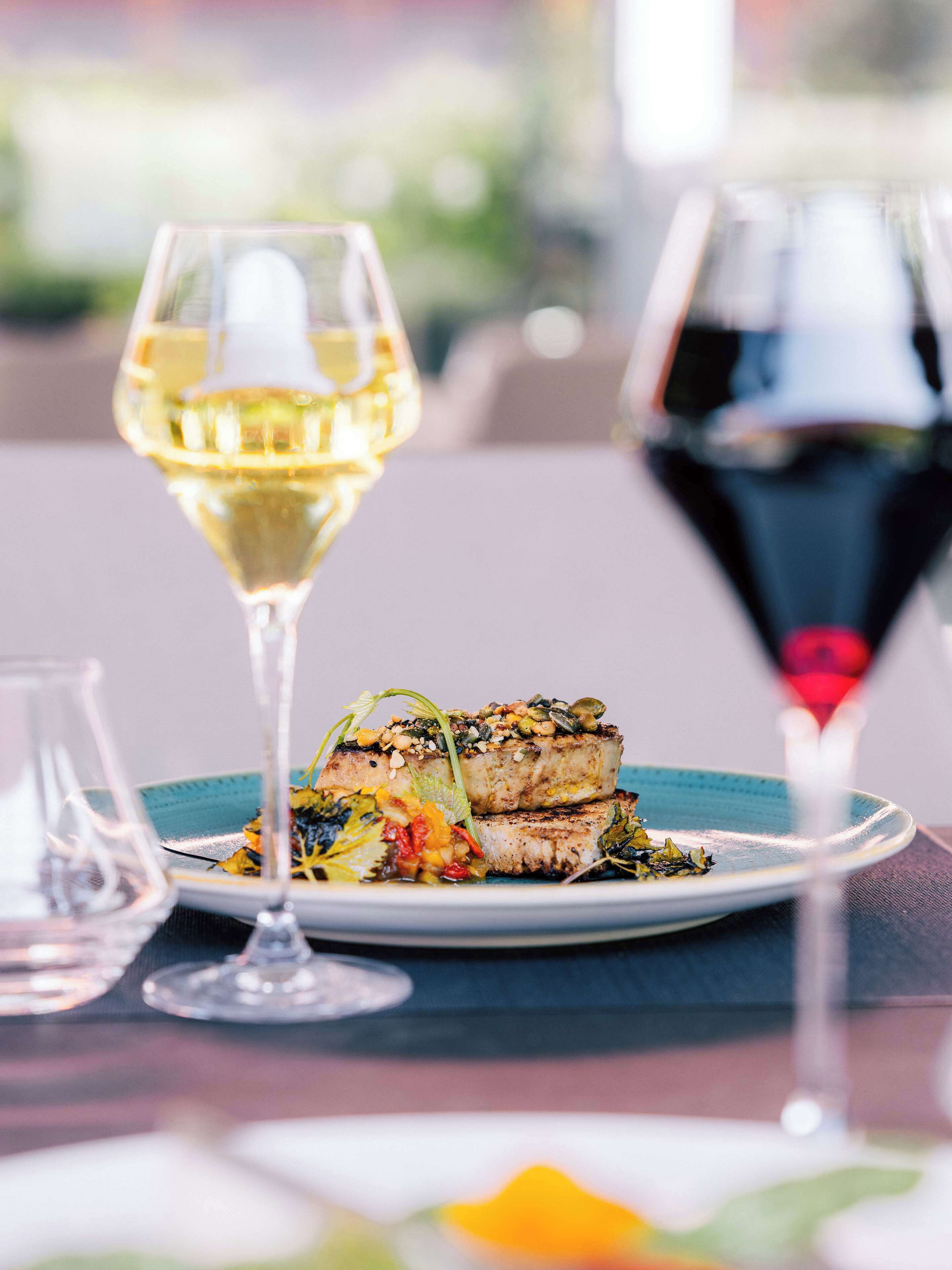 A dining table with a plate of food and two wine glasses.