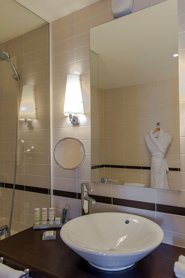 A bathroom with a large mirror, a round sink, and a towel rack.