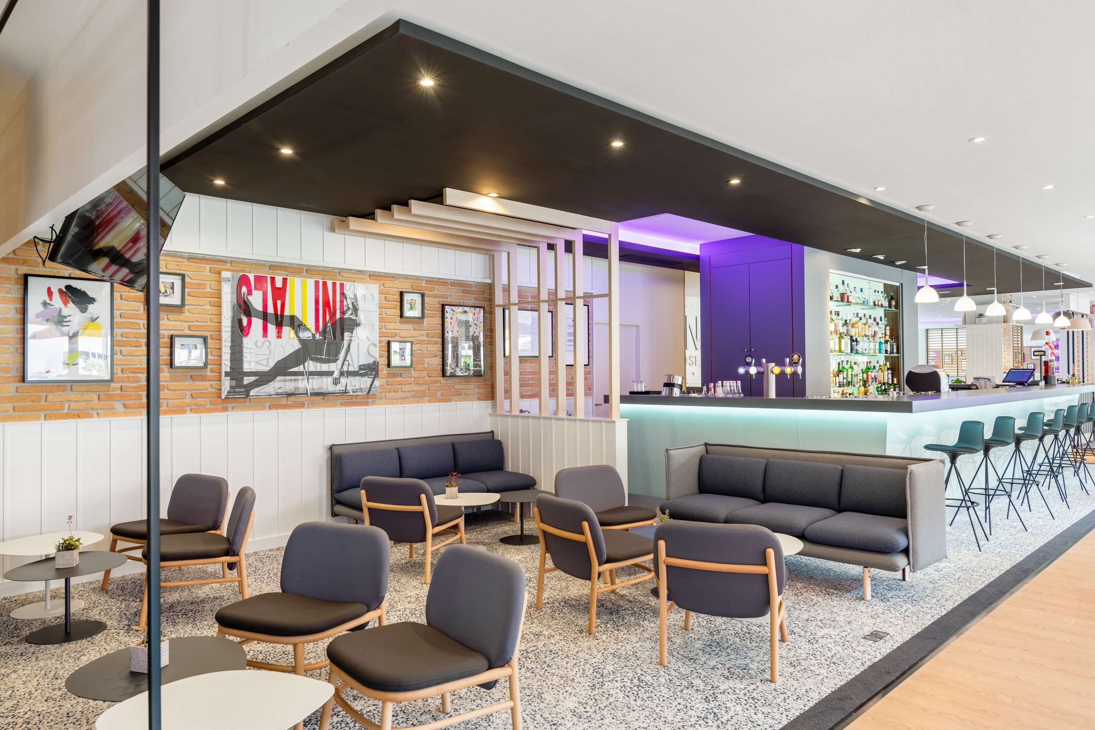 A modern lounge area with seating, a bar, and a wall with artwork.