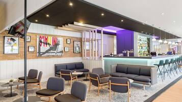 A modern lounge area with seating, a bar, and a wall with artwork.