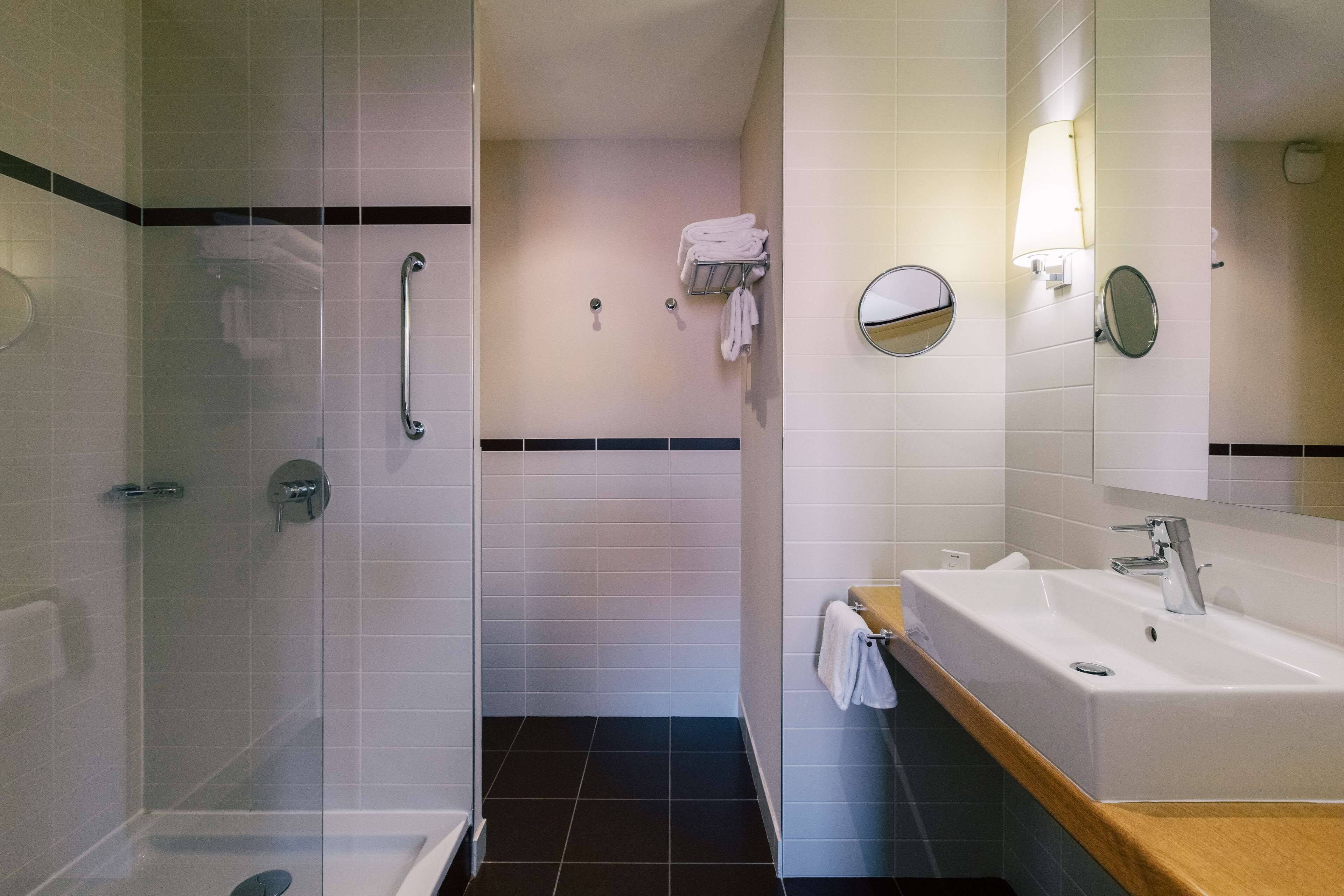 A modern bathroom with a glass-enclosed shower, a sink with a mirror, and a towel rack.