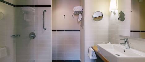 A modern bathroom with a glass-enclosed shower, a sink with a mirror, and a towel rack.