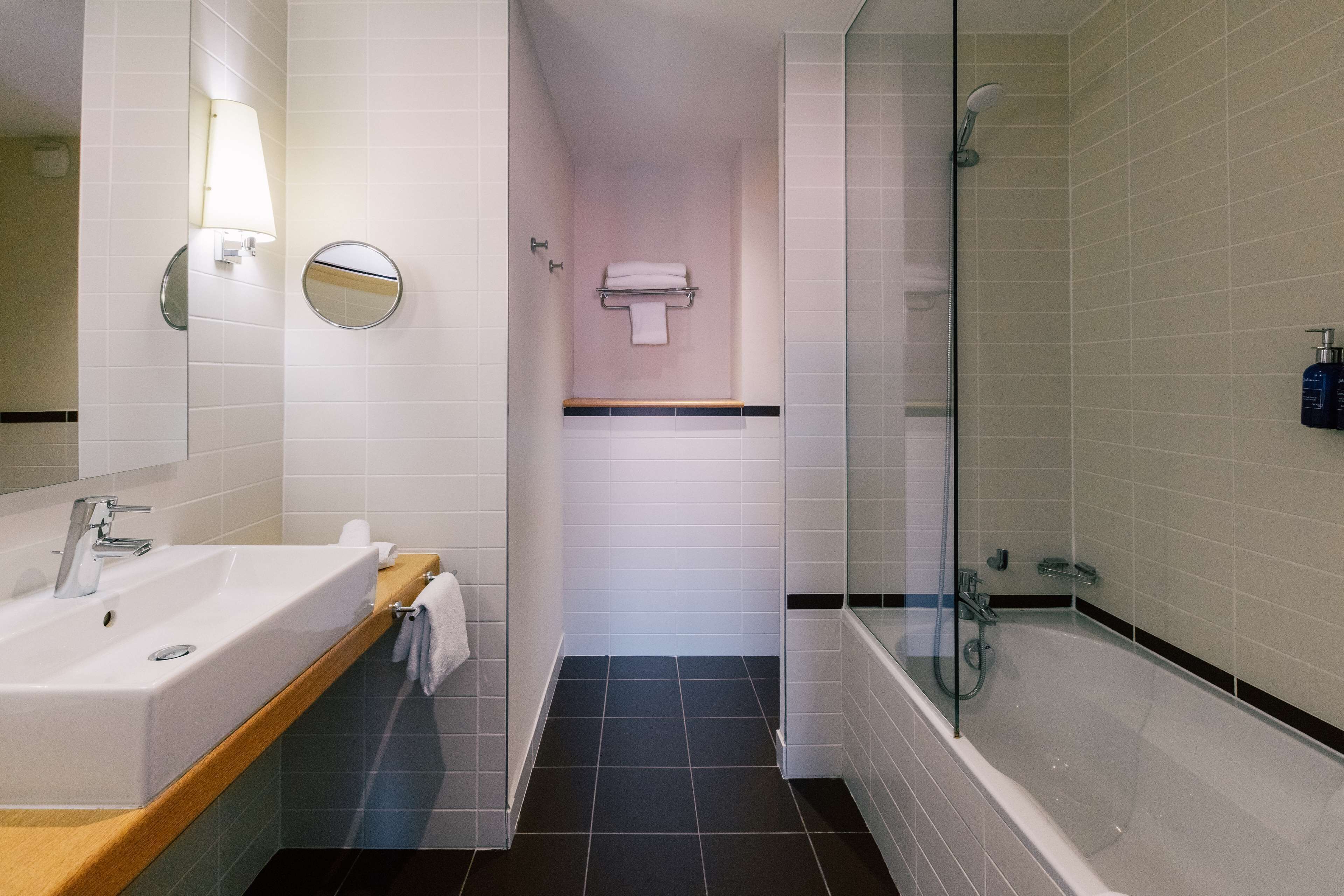 A modern bathroom with a sink, mirror, and glass-enclosed shower.