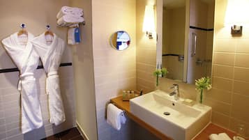Un baño con lavamanos, espejo, toallero y artículos de aseo.